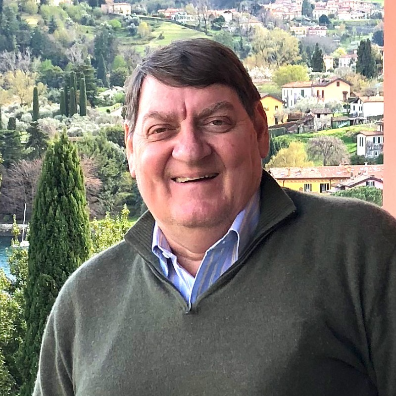 An image of a smiling Doug in front of a hilly European landscape.